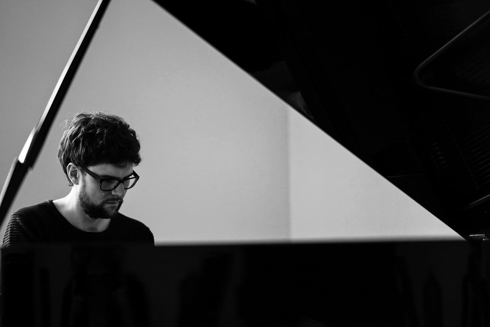 Blick auf den Pianisten Philipp Hermann durch den geöffneten Flügel hindurch